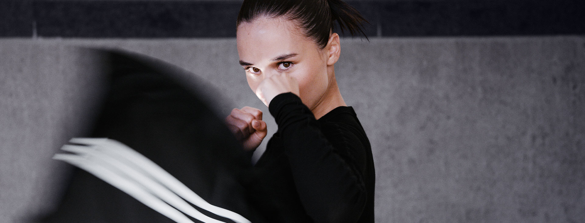 A boxing woman looks directly into the camera while kicking (Photo)