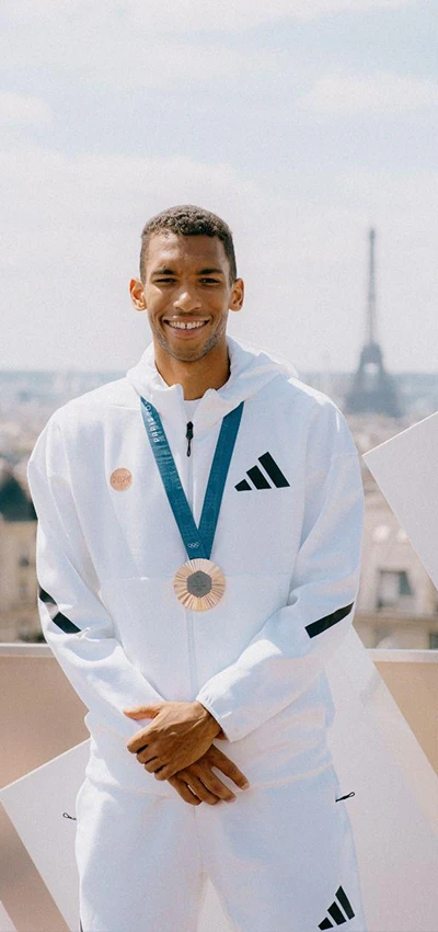This image shows a group of people outdoors, standing and posing with a building and greenery in the background. 
