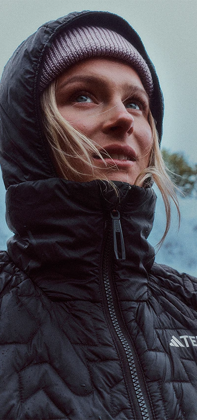 The image is a close-up portrait of a woman wearing a black puffer jacker, looking away from the camera.