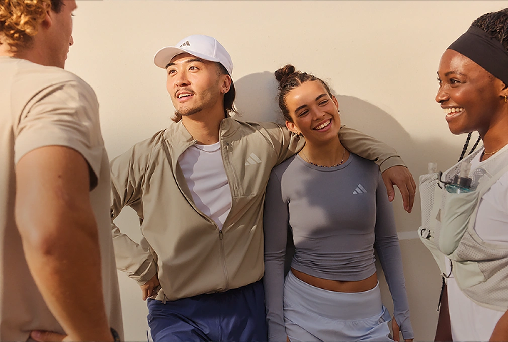 Gruppe junger Menschen in adidas Sportbekleidung im Gespräch. (Foto)