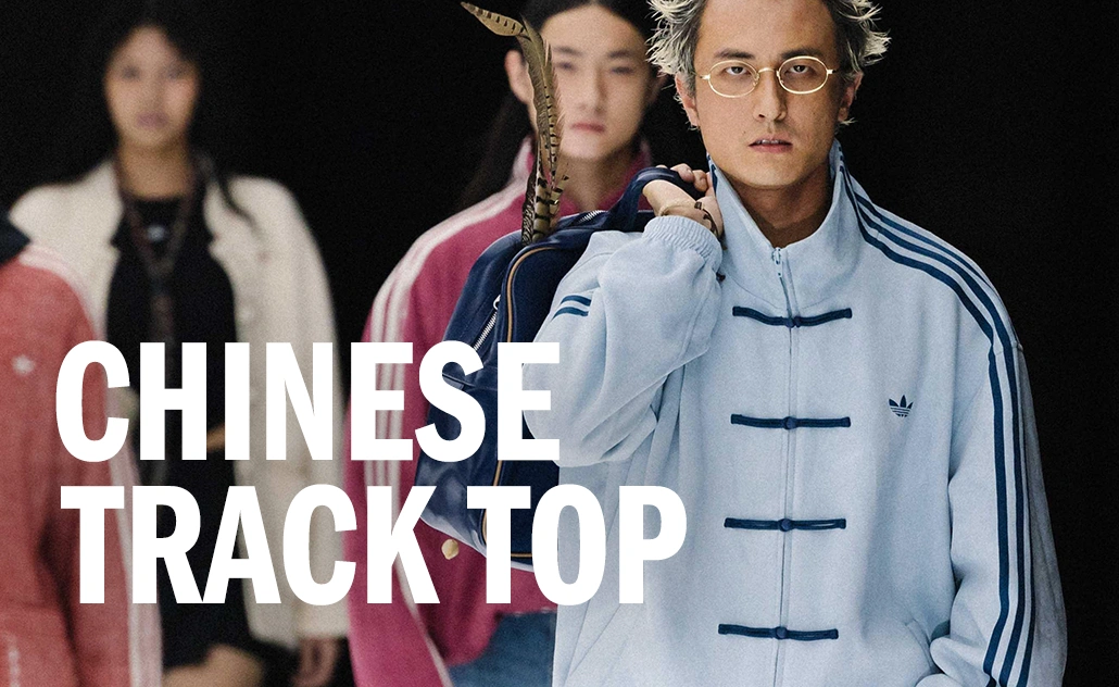 Mann trägt eine hellblaue adidas Trainingsjacke im chinesisch inspirierten Design, mit Schriftzug „Chinese Track Top“. (Foto)