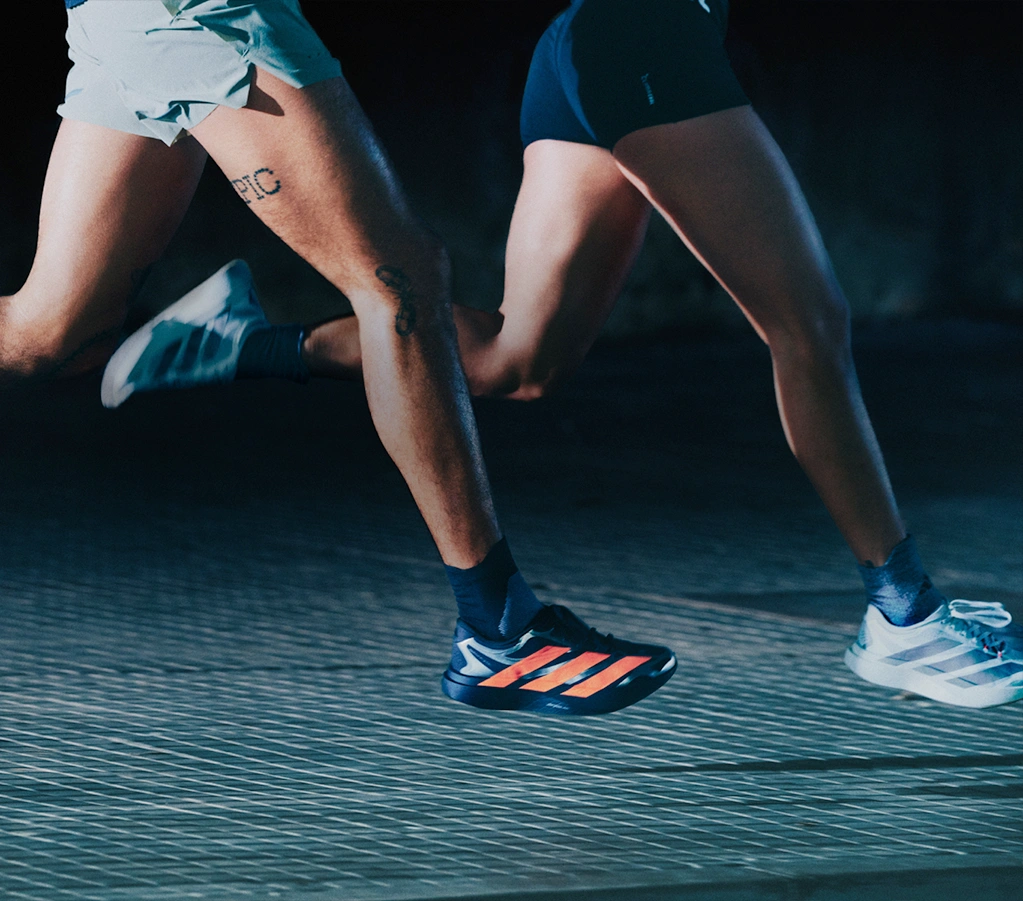 Two people running side by side wearing adidas running shoes. (Photo)