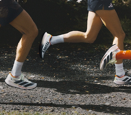 Two people running on a forest path wearing adidas shoes. (Photo)