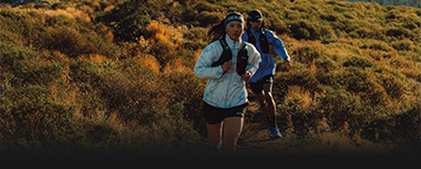 Two runners trail running in a mountainous landscape. (Photo)