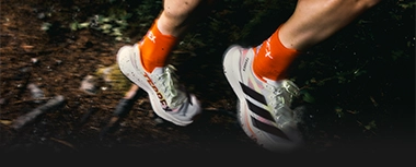 Runner wearing adidas shoes on a forest trail. (Photo)