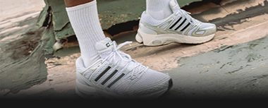 Person wearing white adidas sneakers in an urban setting. (Photo)