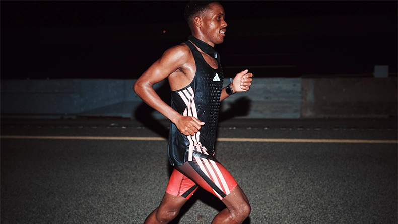 Single male runner at night on a road, wearing a black singlet and red shorts. (Photo)