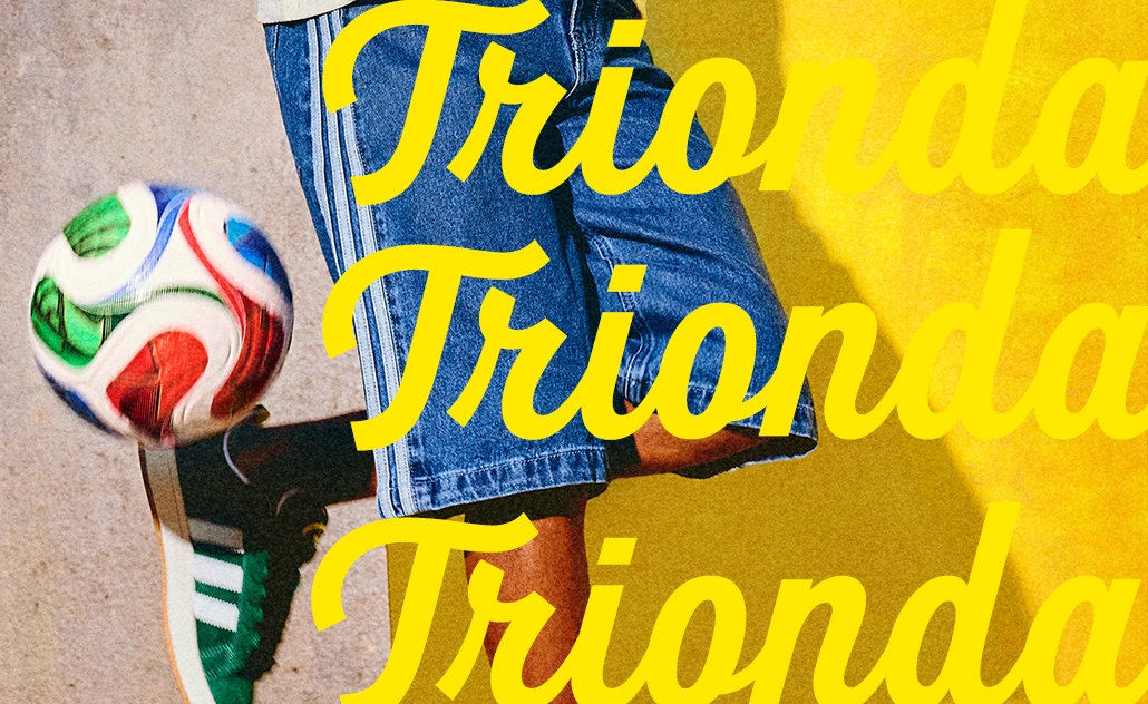 Person wearing jeans and green adidas sneakers balancing a football, with large “Trionda” lettering. (Photo)